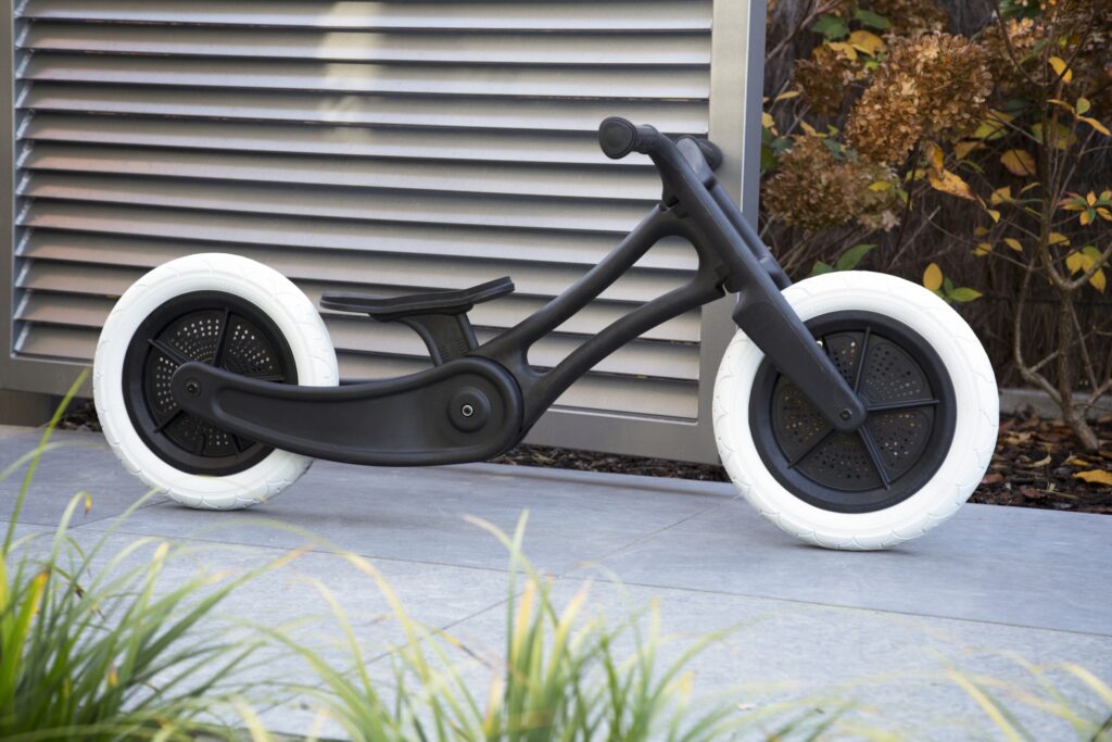 Finished balance bike in an outdoor setting, displaying the sleek design, recycled materials, and signature Wishbone aesthetic.