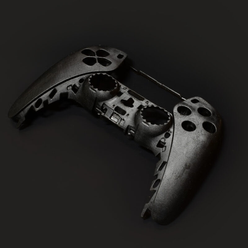 A disassembled black video game controller shell, missing buttons and internal components, is displayed on a dark background—an example of Industrial Design NZ with an emphasis on Design for Manufacture.
