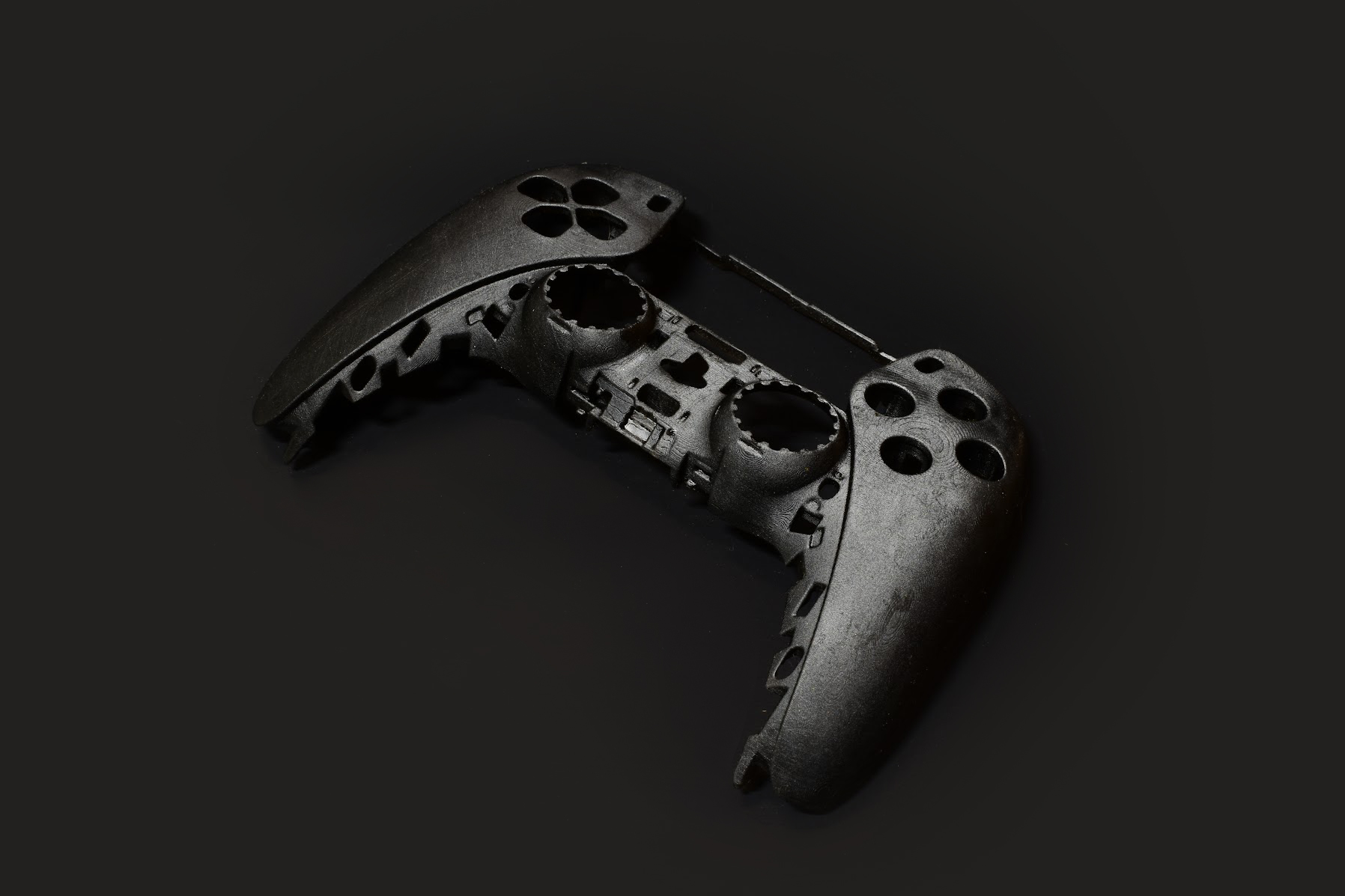 A disassembled black video game controller shell, missing buttons and internal components, is displayed on a dark background—an example of Industrial Design NZ with an emphasis on Design for Manufacture.